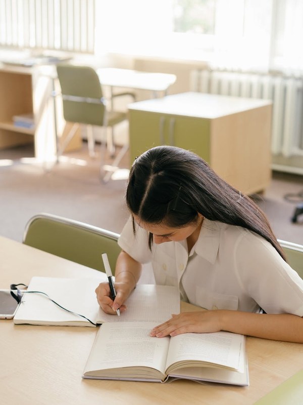 Jovem universitária estudando com livro e caderno em sala de aula